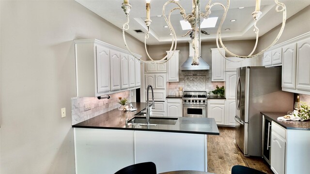 kitchen featuring a sink, stainless steel appliances, dark countertops, a peninsula, and recessed lighting