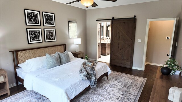 bedroom featuring a barn door, wood finished floors, baseboards, connected bathroom, and a ceiling fan