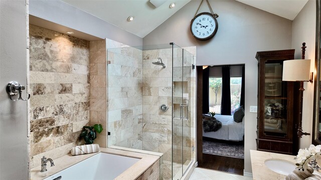 ensuite bathroom featuring a stall shower, vaulted ceiling, a bath, and vanity