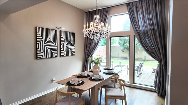 dining room with a chandelier, wood finished floors, baseboards, and a towering ceiling