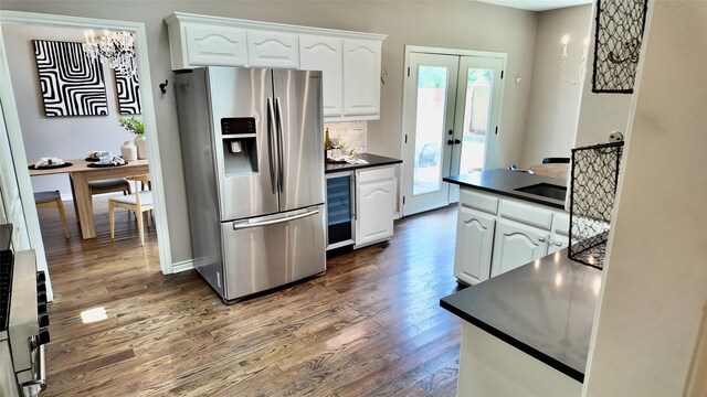 kitchen featuring stainless steel fridge, dark countertops, dark wood-type flooring, white cabinets, and a chandelier