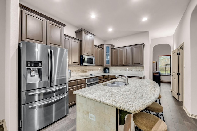 kitchen with stainless steel appliances, a sink, arched walkways, backsplash, and recessed lighting