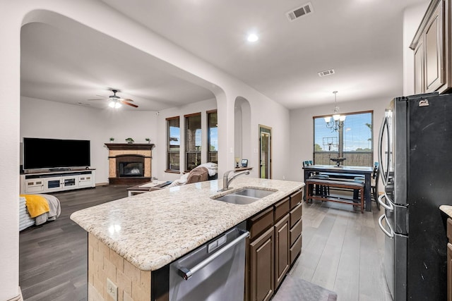 kitchen with appliances with stainless steel finishes, a sink, an island with sink, dark wood finished floors, and a ceiling fan