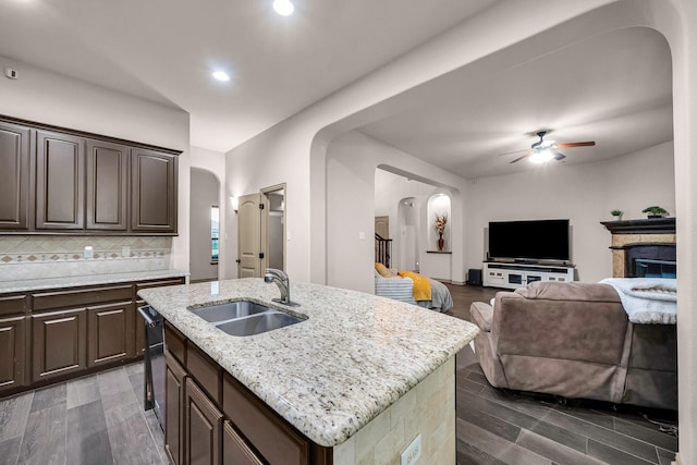 kitchen with a sink, arched walkways, a ceiling fan, dark brown cabinets, and recessed lighting