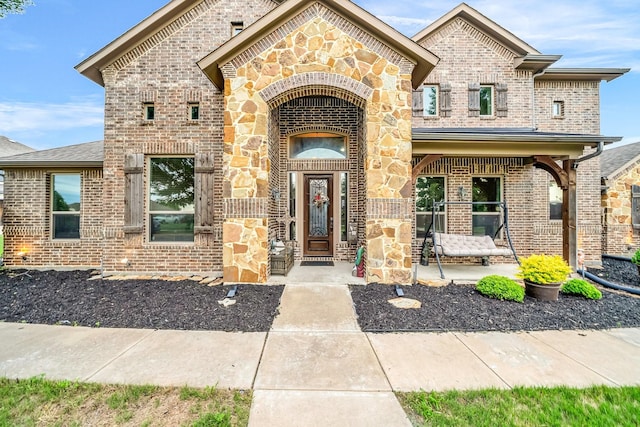 view of front of home with brick siding, stone siding, and covered porch