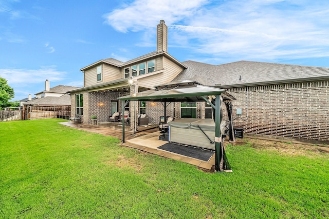 back of property with a hot tub, brick siding, a patio, a gazebo, and a chimney