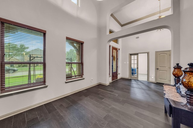 entrance foyer featuring dark wood-type flooring, a high ceiling, arched walkways, and baseboards