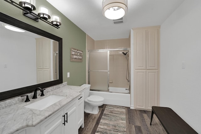 full bathroom with wood finished floors, vanity, combined bath / shower with glass door, and toilet