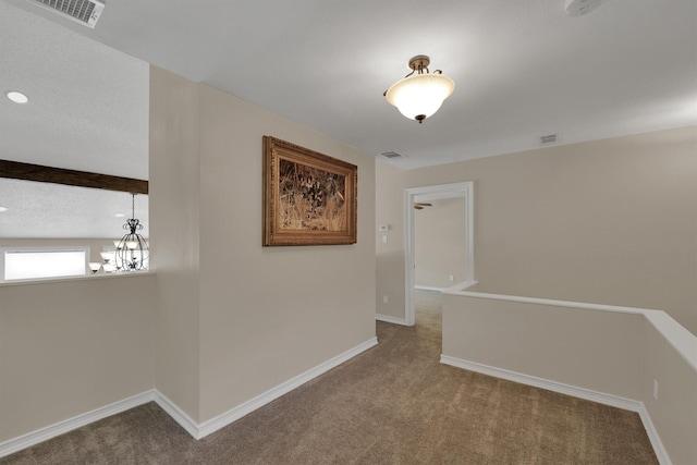 hall featuring carpet flooring, a chandelier, baseboards, and an upstairs landing