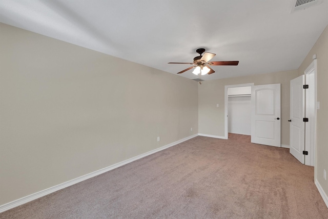 unfurnished bedroom featuring light carpet, baseboards, a ceiling fan, and a spacious closet