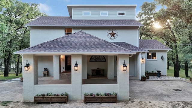 view of front of house with a shingled roof and brick siding
