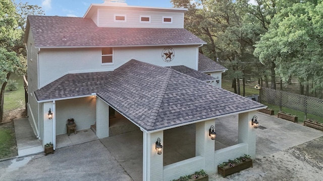 view of side of home featuring roof with shingles and fence