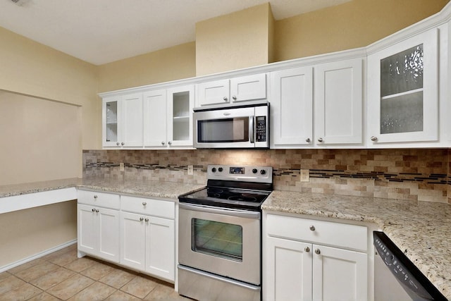 kitchen with appliances with stainless steel finishes, white cabinets, backsplash, and light tile patterned floors