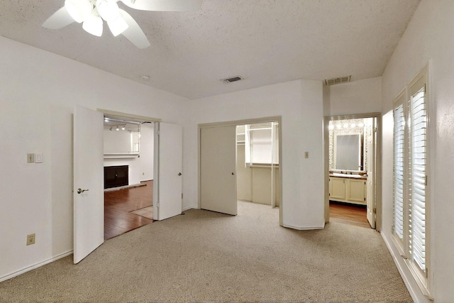 unfurnished bedroom featuring carpet, multiple windows, a ceiling fan, and ensuite bathroom