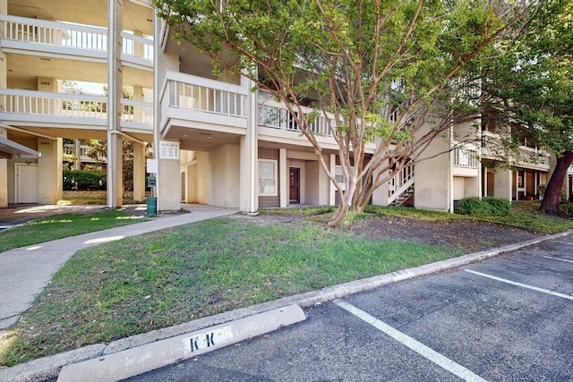 view of property with uncovered parking and stairway