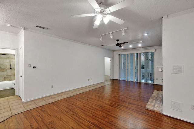 empty room with ceiling fan, wood finished floors, a textured ceiling, ornamental molding, and track lighting