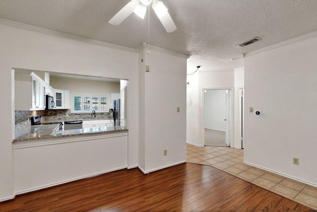 unfurnished living room with wood finished floors, ceiling fan, crown molding, a textured ceiling, and a sink