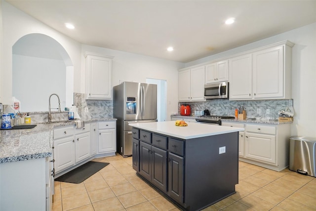 8652 Fernhill Dr, Fort Worth, TX 76123 - kitchen featuring appliances with stainless steel finishes, a kitchen island, white cabinetry, light tile patterned floors, and tasteful backsplash