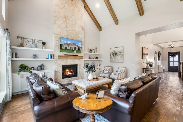 living room featuring wood finished floors, high vaulted ceiling, beamed ceiling, a fireplace, and arched walkways