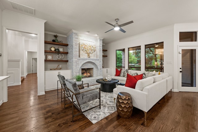 living room featuring dark wood finished floors, a fireplace, ornamental molding, a ceiling fan, and baseboards