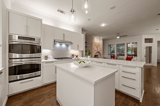 kitchen with stainless steel appliances, a ceiling fan, light countertops, ornamental molding, and open floor plan