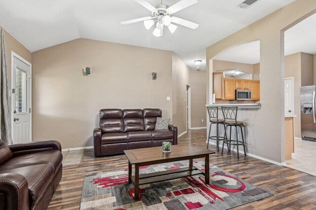 8833 Stirrup Way, Fort Worth, TX 76244 - living area featuring a ceiling fan, lofted ceiling, arched walkways, wood finished floors, and baseboards