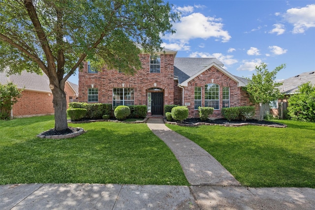 traditional-style home featuring brick siding, a front yard, and a shingled roof