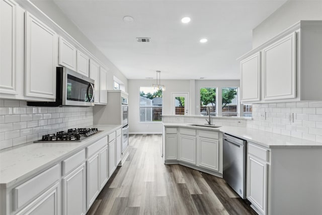kitchen with stainless steel appliances, a sink, a peninsula, recessed lighting, and dark wood finished floors