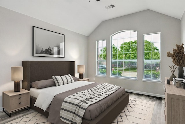 bedroom featuring light wood-style flooring, lofted ceiling, and baseboards