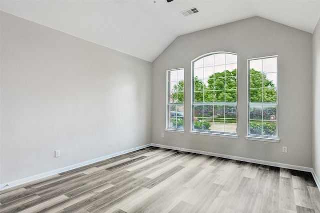 empty room with light wood-style floors, ceiling fan, vaulted ceiling, and baseboards