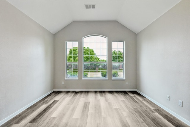 spare room with wood finished floors, baseboards, and vaulted ceiling