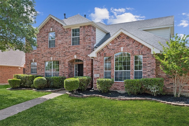 traditional-style house with a front yard, brick siding, and roof with shingles