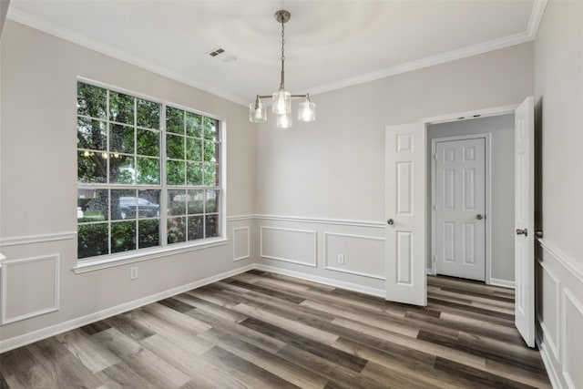 unfurnished dining area featuring ornamental molding, wood finished floors, a decorative wall, a chandelier, and wainscoting
