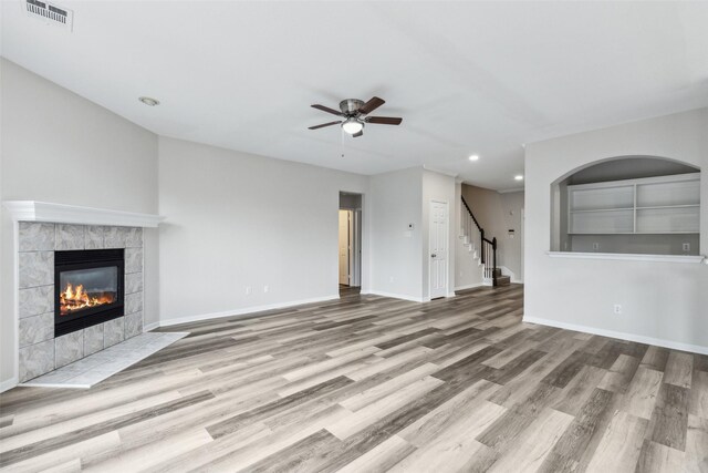 unfurnished living room featuring ceiling fan, recessed lighting, wood finished floors, a fireplace, and stairway
