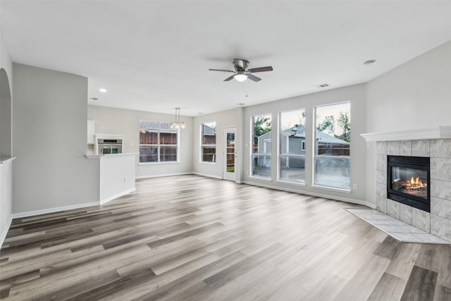 unfurnished living room featuring a fireplace, healthy amount of natural light, a ceiling fan, wood finished floors, and recessed lighting