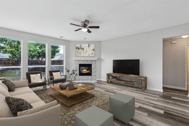 living room featuring a ceiling fan, wood finished floors, a fireplace, and baseboards