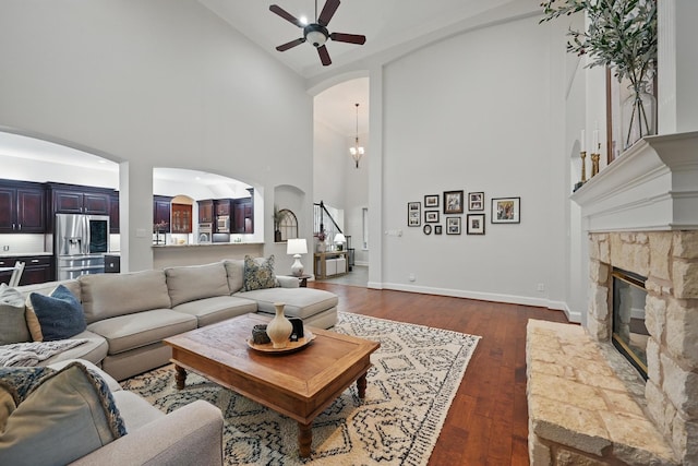 2099 Remington Ln, Frisco, TX 75033 - living area with high vaulted ceiling, a fireplace, a ceiling fan, arched walkways, and dark wood-type flooring