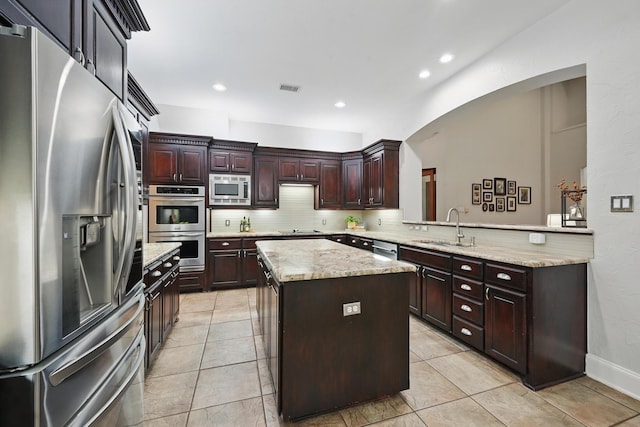 2099 Remington Ln, Frisco, TX 75033 - kitchen with stainless steel appliances, a sink, tasteful backsplash, a center island, and arched walkways