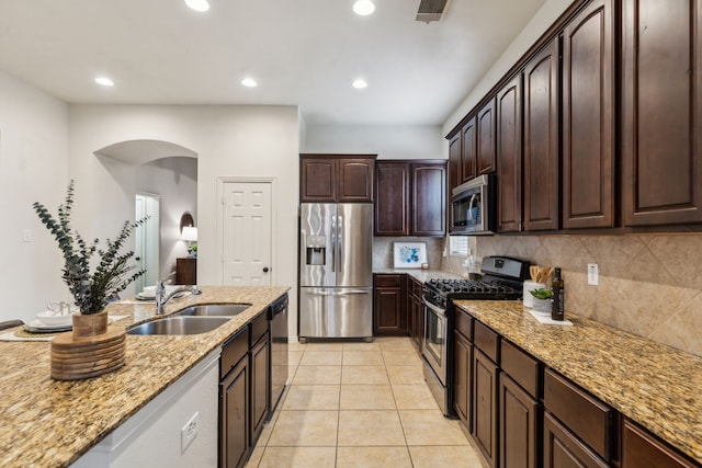 kitchen featuring stainless steel appliances, a sink, light stone counters, tasteful backsplash, and recessed lighting
