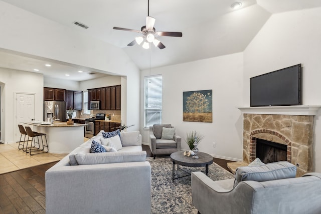 living area with light wood finished floors, ceiling fan, vaulted ceiling, a fireplace, and recessed lighting