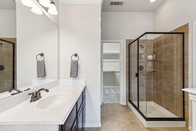 bathroom featuring a stall shower, tile patterned floors, a spacious closet, vanity, and baseboards