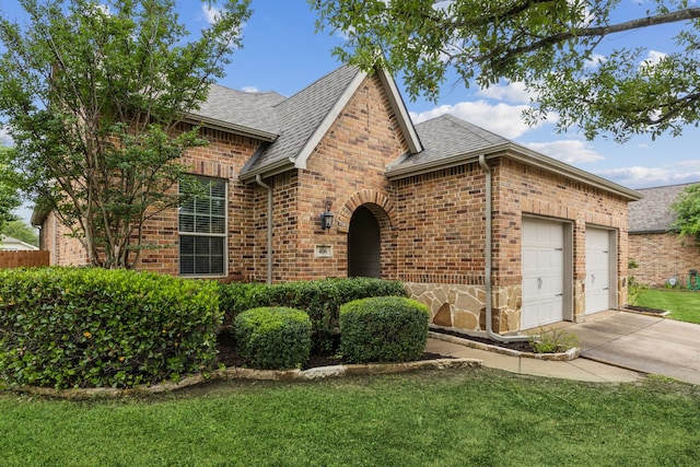 view of front of home featuring brick siding, roof with shingles, an attached garage, concrete driveway, and a front lawn