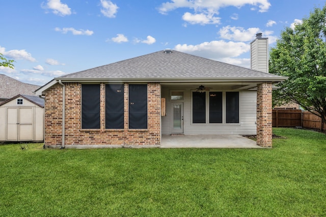 back of property with a patio area, a storage shed, a shingled roof, a chimney, and an outbuilding