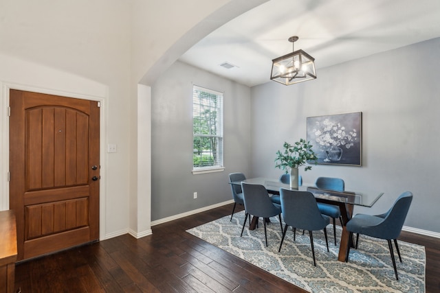 dining area with arched walkways, dark wood-style floors, a chandelier, and baseboards
