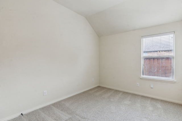 empty room featuring carpet, lofted ceiling, and baseboards