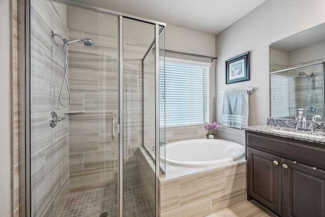 bathroom featuring a stall shower, a bath, and vanity