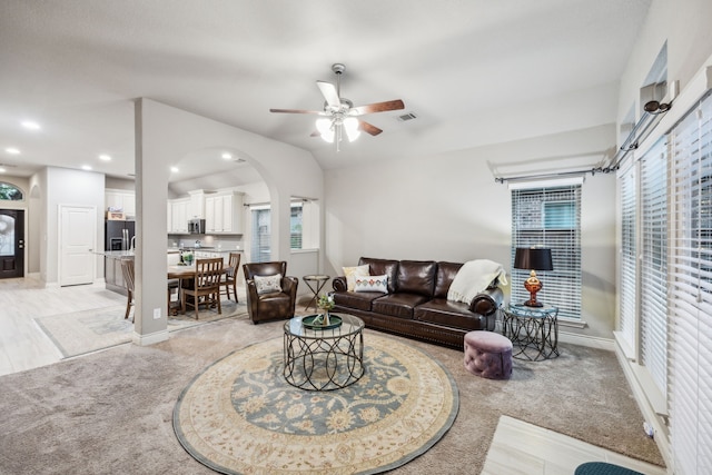 living room with light carpet, ceiling fan, arched walkways, recessed lighting, and baseboards