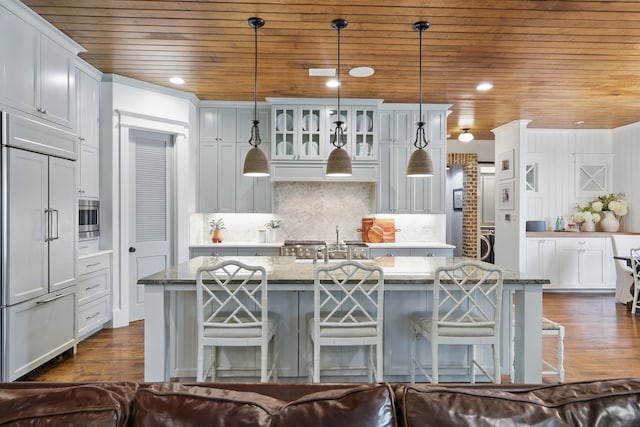 304 Nora Ln, Argyle, TX 76226 - kitchen with built in appliances, wood ceiling, a kitchen island with sink, dark wood finished floors, and light stone countertops
