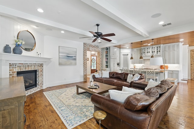 304 Nora Ln, Argyle, TX 76226 - living area featuring beamed ceiling, ceiling fan, wood finished floors, a brick fireplace, and baseboards