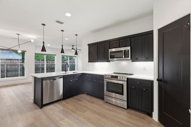 1967 Bayside St, Dallas, TX 75212 - kitchen featuring stainless steel appliances, a sink, light wood-style floors, a peninsula, and recessed lighting
